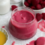 vibrant, sweet, tart, eggless raspberry curd fills a glass jar with its smooth and creamy nature.