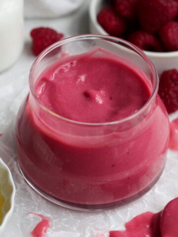 vibrant, sweet, tart, eggless raspberry curd fills a glass jar with its smooth and creamy nature.