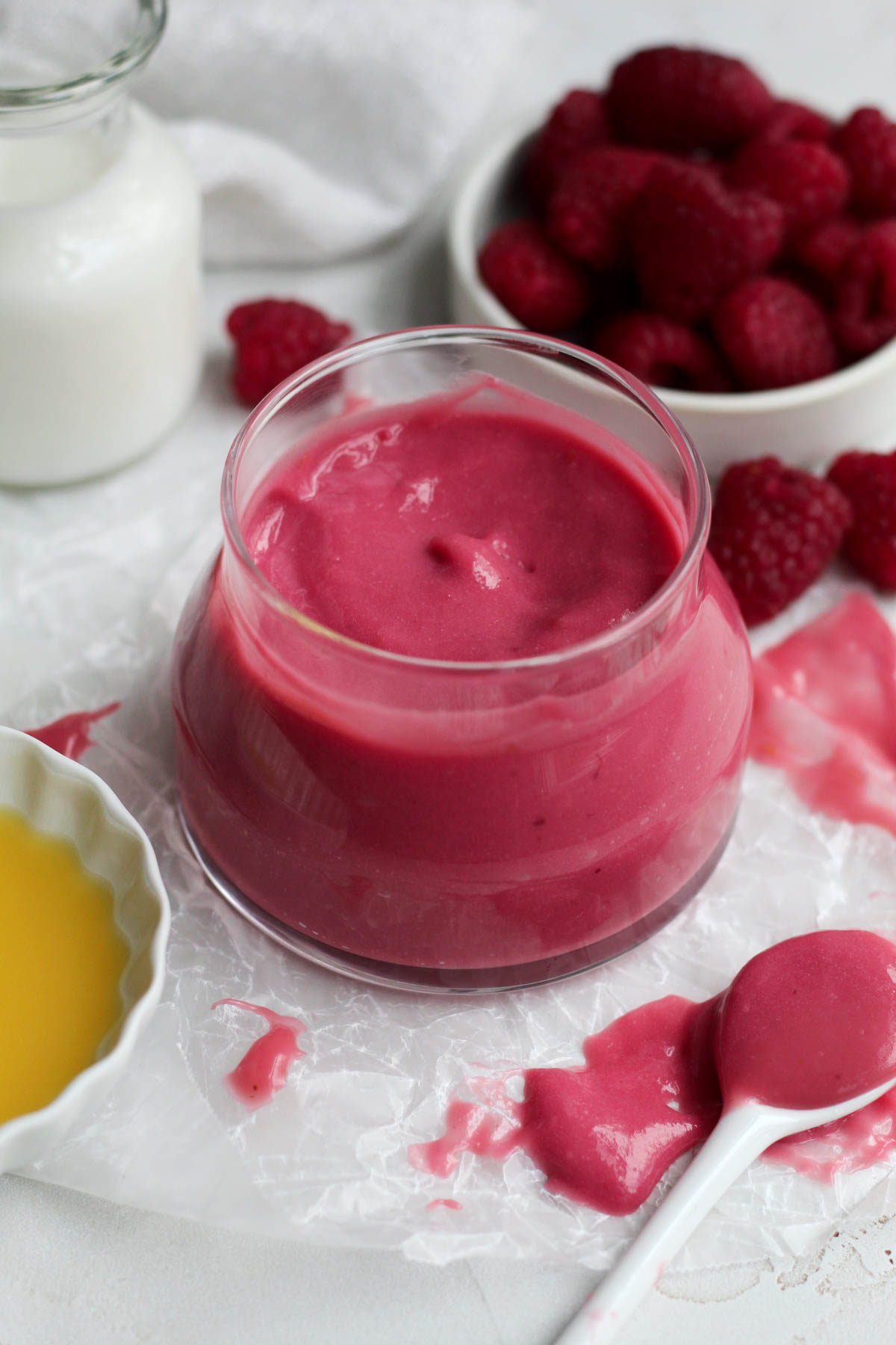 a bowl of bright pink raspberry curd in a clear jar.