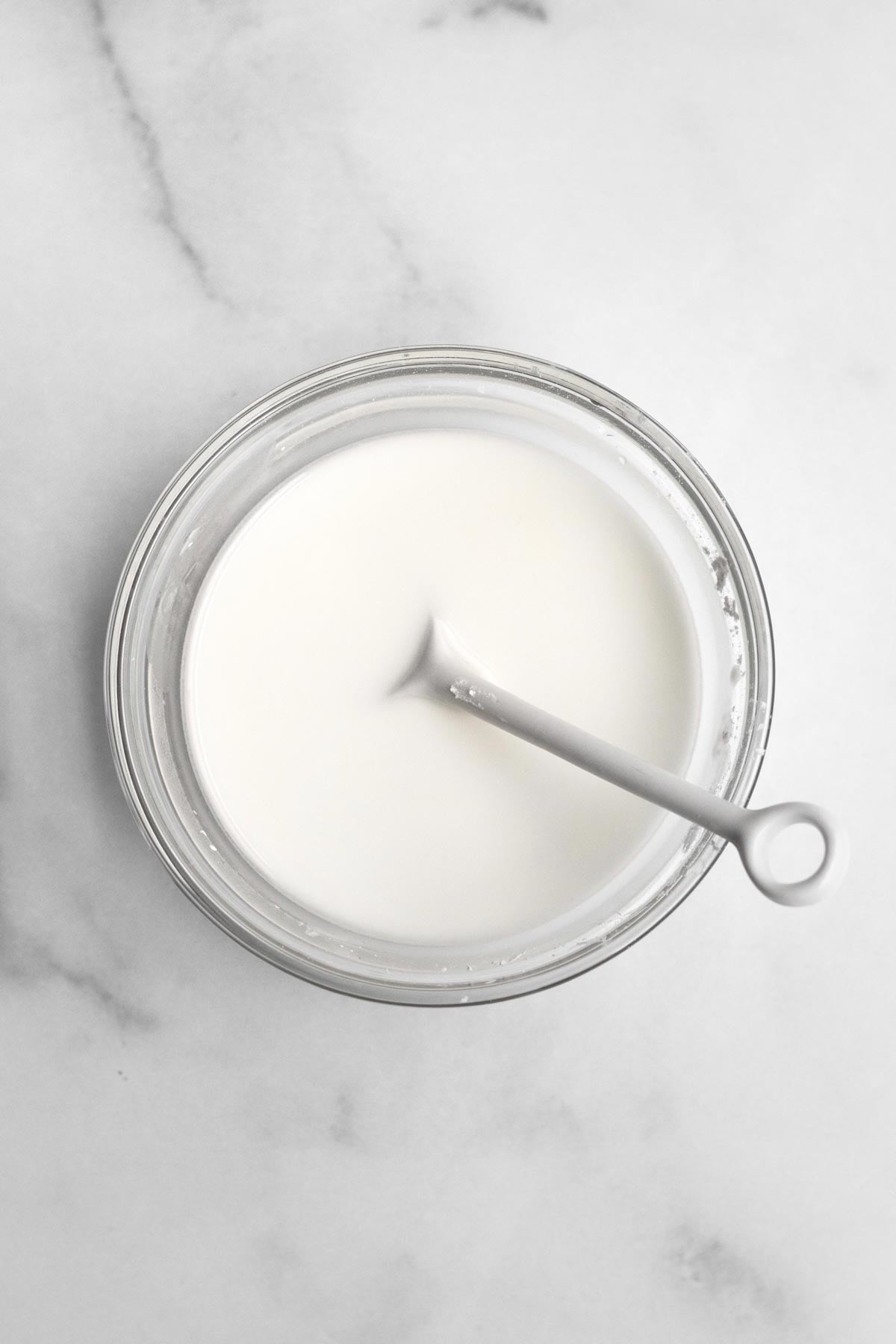 Milky white cornstarch water in a bowl with a spoon.