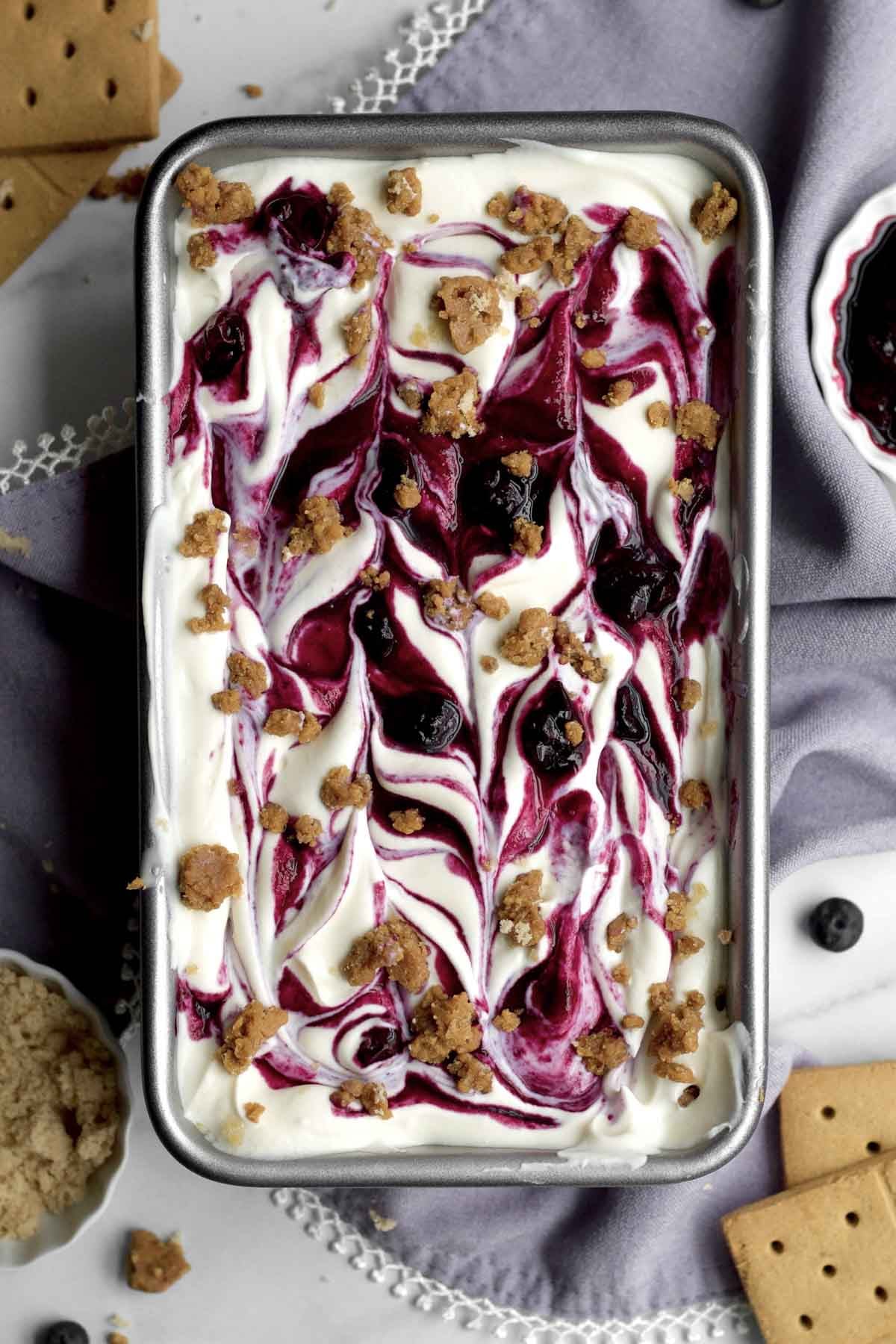 luscious blueberry cheesecake ice cream in a loaf pan with gluten-free graham cracker crumbles.