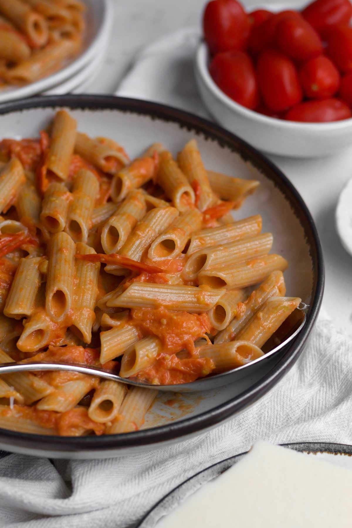 Easy, orange-hued, creamy cherry tomato pasta in a rustic bowl.