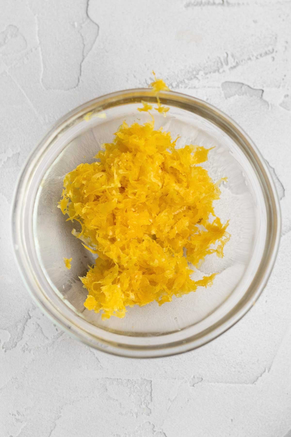 Bright yellow lemon zest in a glass bowl.