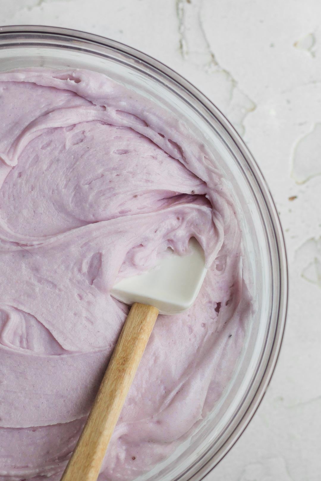 Creamy lavender blueberry frosting mixed smooth with a spatula.