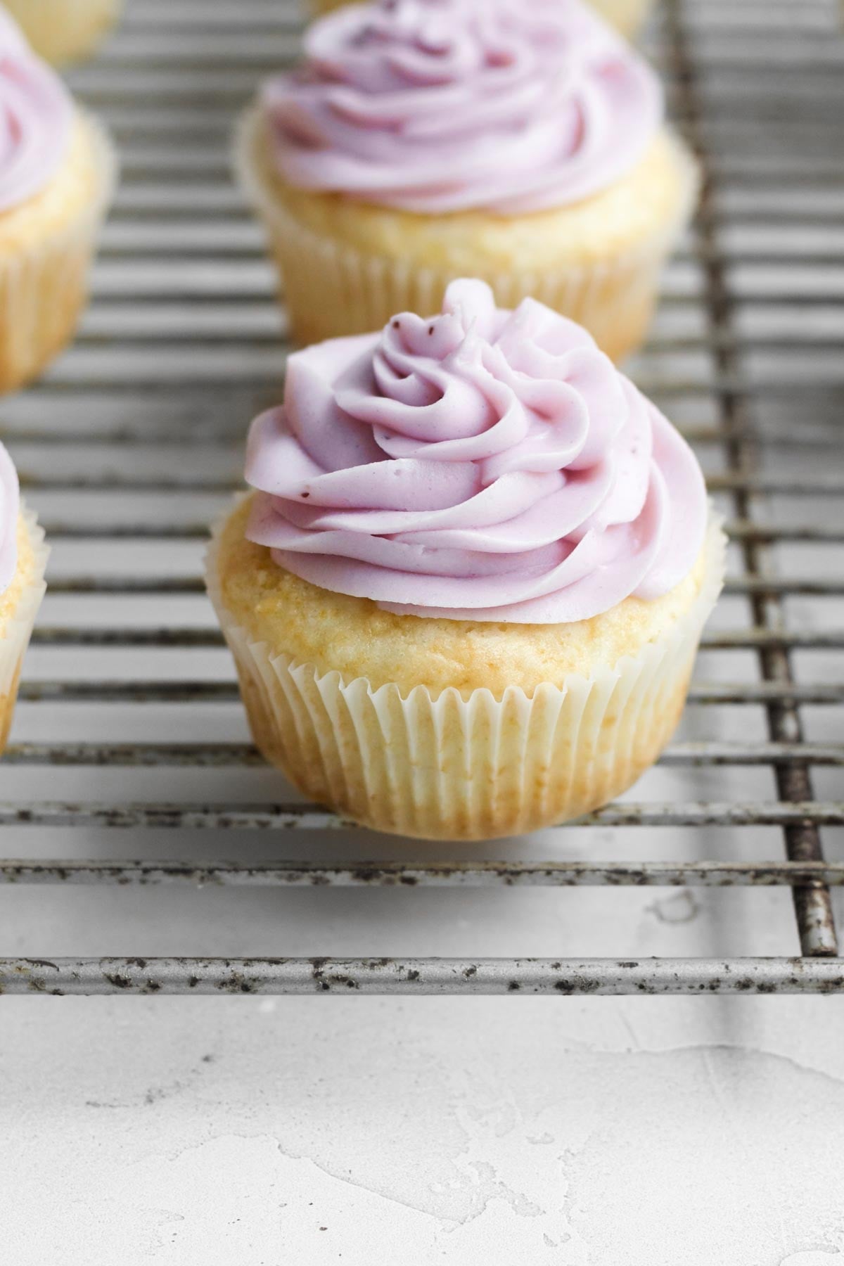 Topping the cupcakes with a swirl of blueberry frosting.