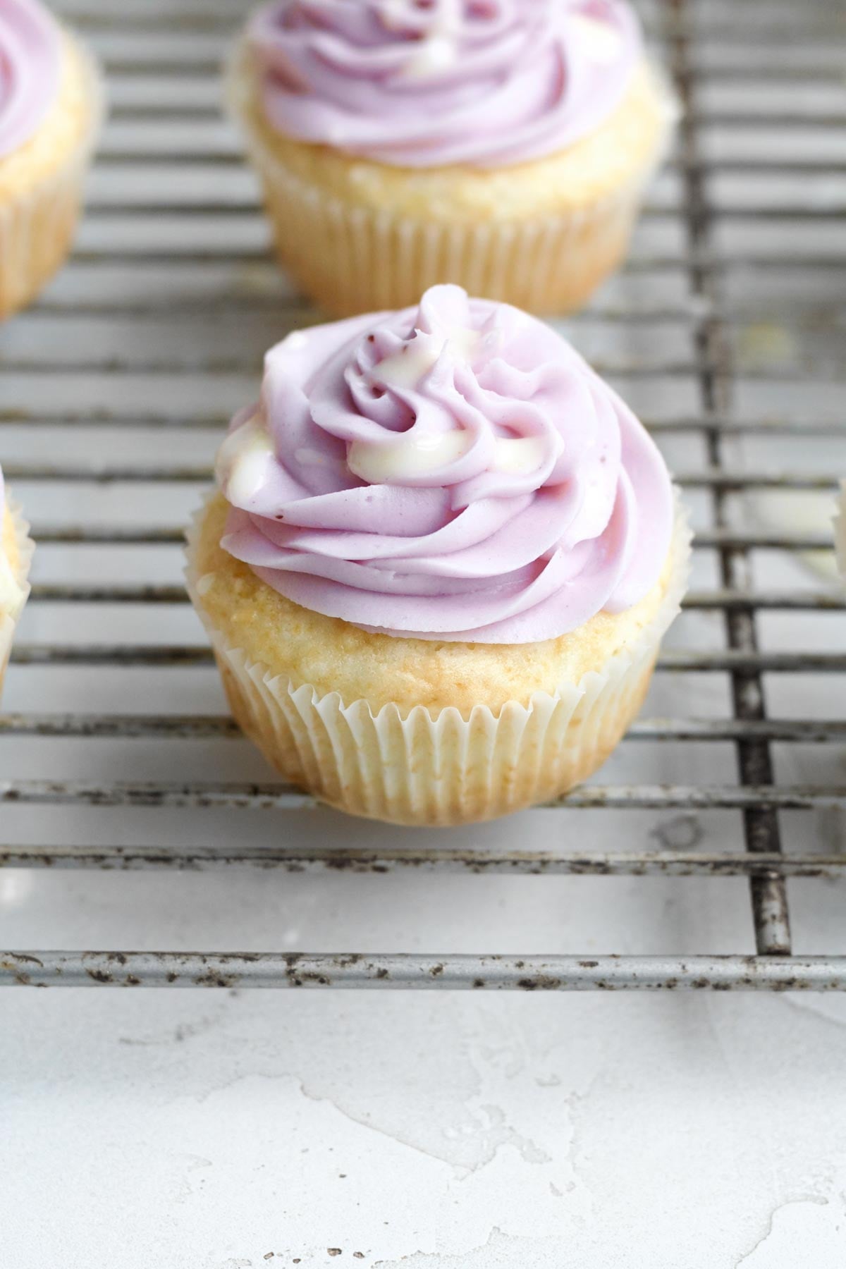 Splattering the lemon glaze across the top of the lemon blueberry cupcakes.
