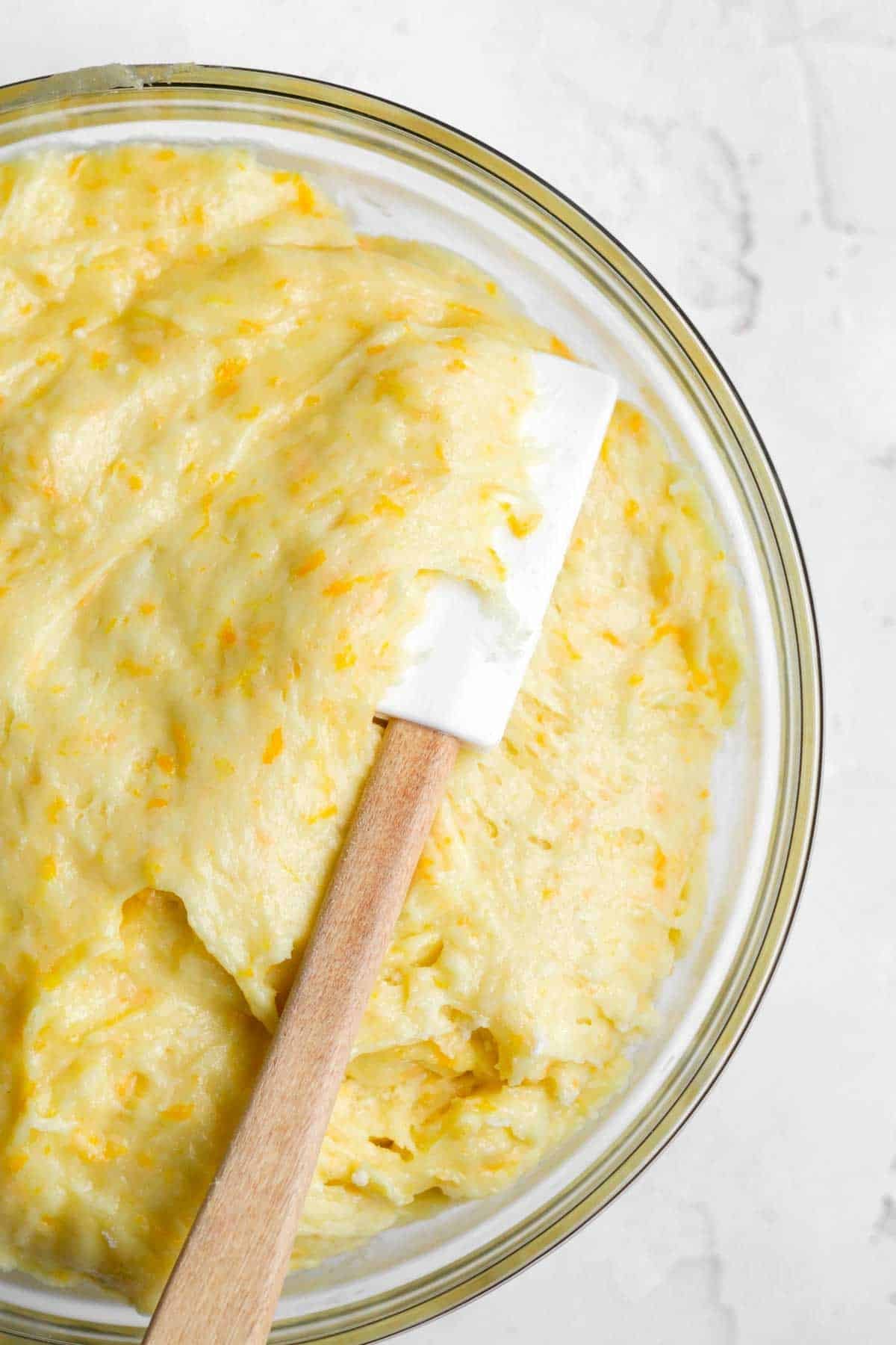 mixing in the dry ingredients with a spatula to make an orange cake batter.