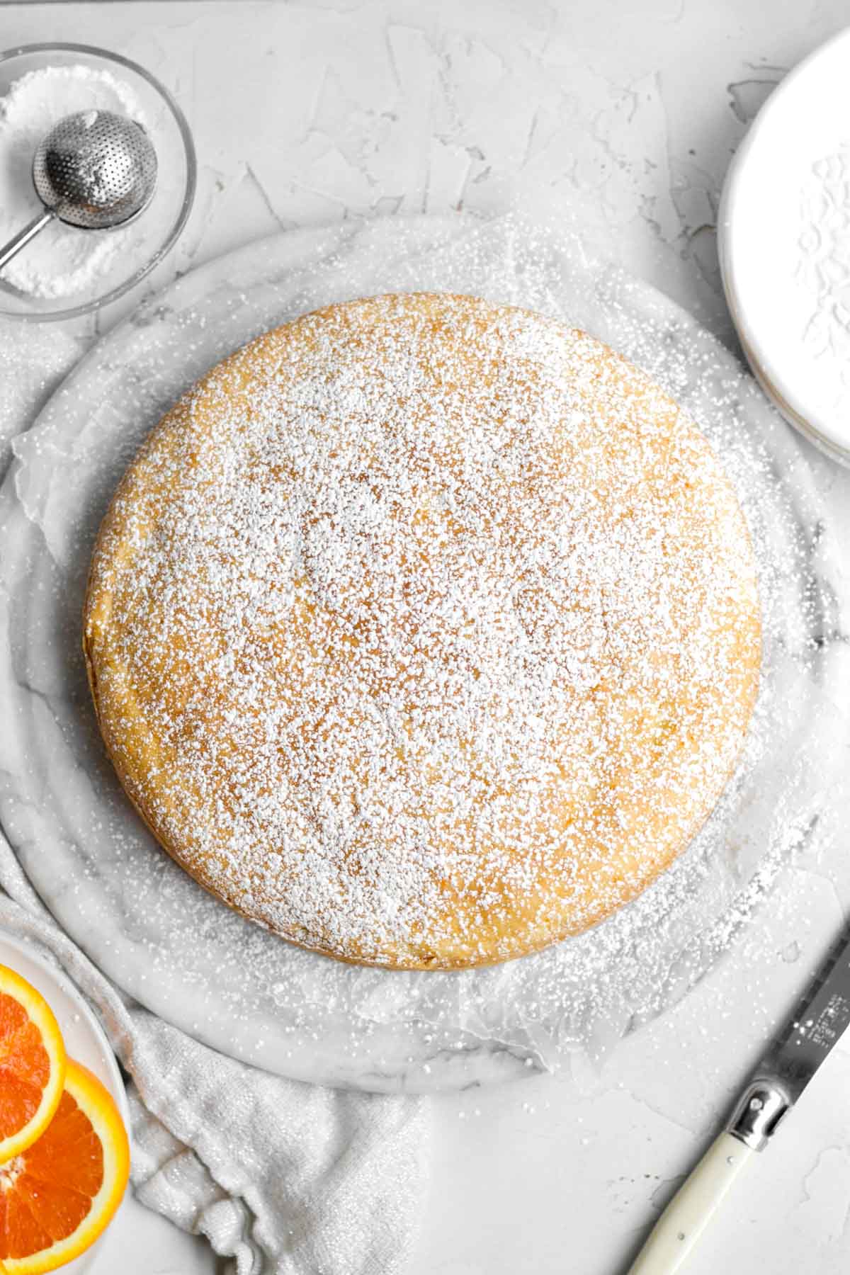 dusting the top of the orange cake with confectioners' sugar.