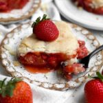 Gluten-free strawberry cobbler slice oozing with warm strawberry filling topped with a fresh strawberry.