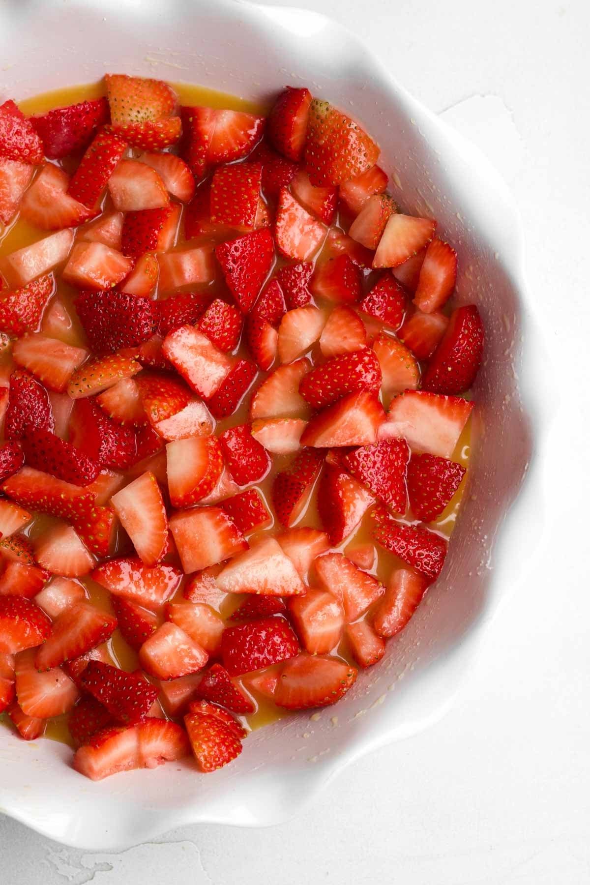Chopped strawberries in a baking dish with orange juice and sugar.