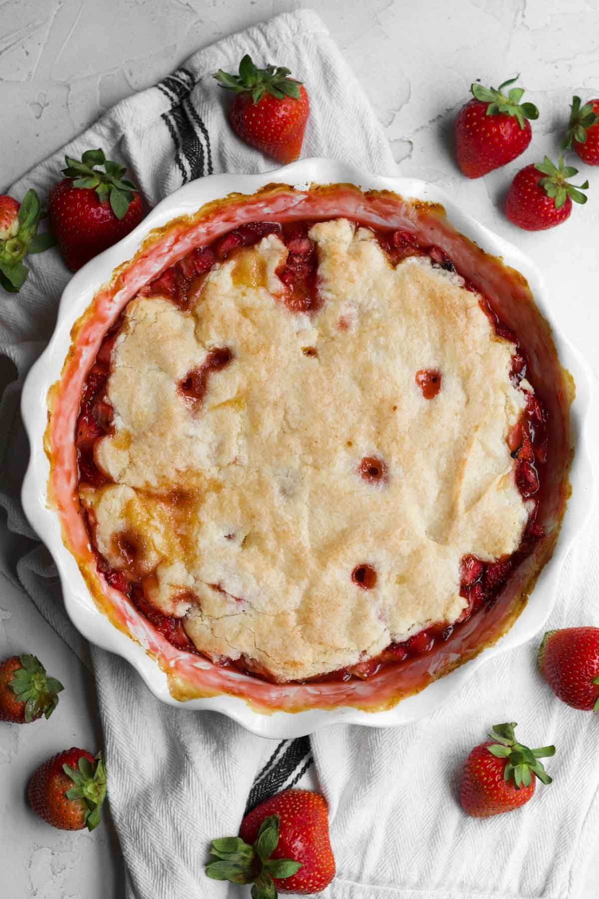 Warm strawberry cobbler in the baking dish with a golden brown crust.