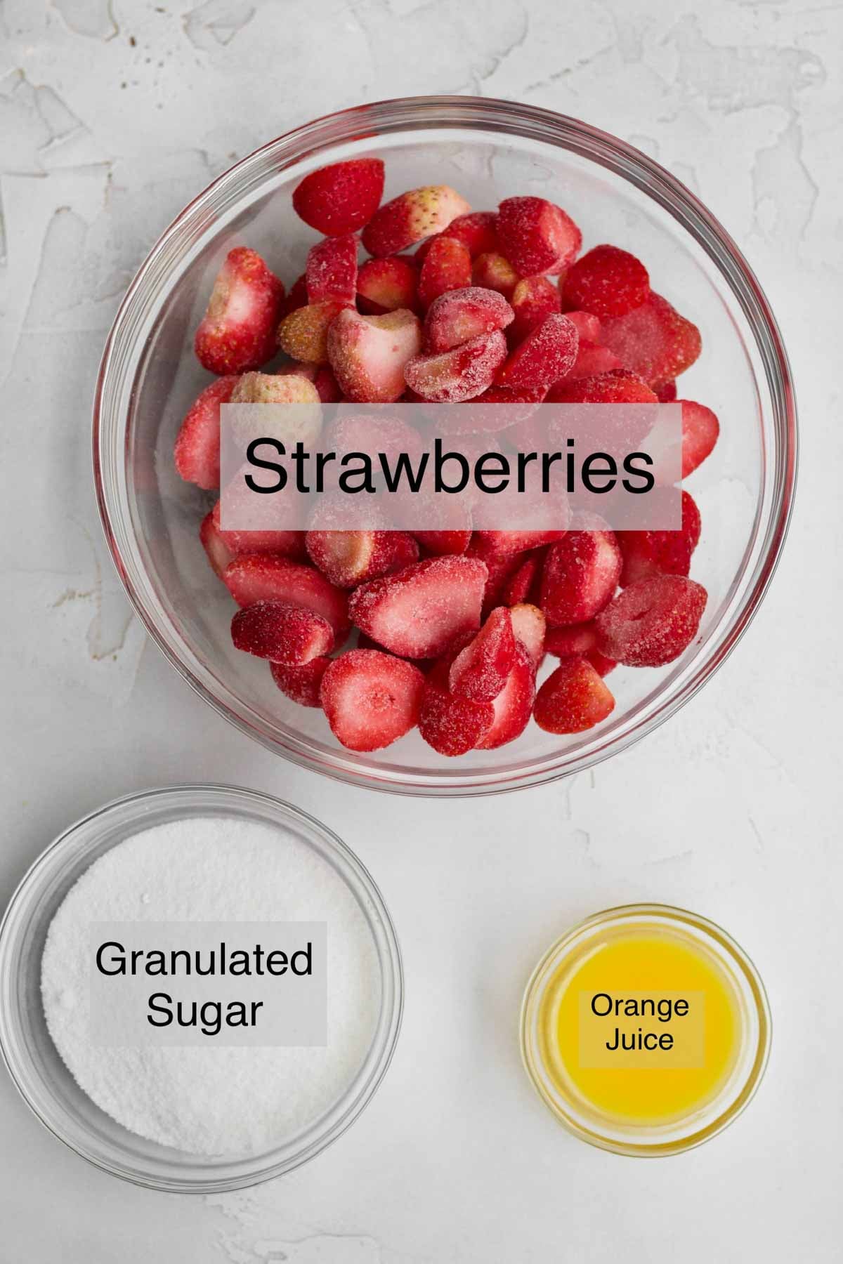 Strawberry syrup ingredients in separate bowls: Frozen strawberries, granulated sugar, and orange juice.