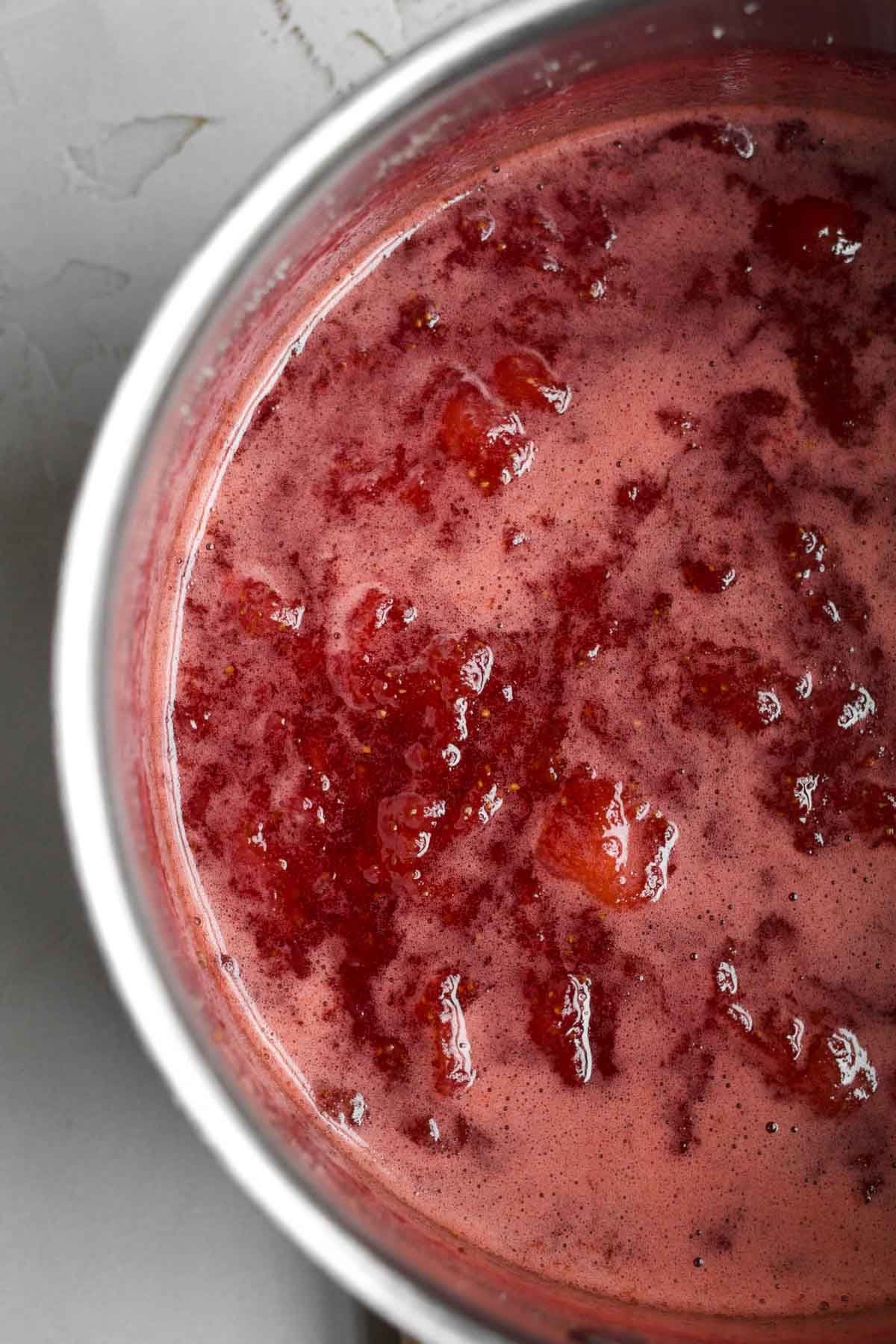 Simmering strawberry syrup in a saucepan.