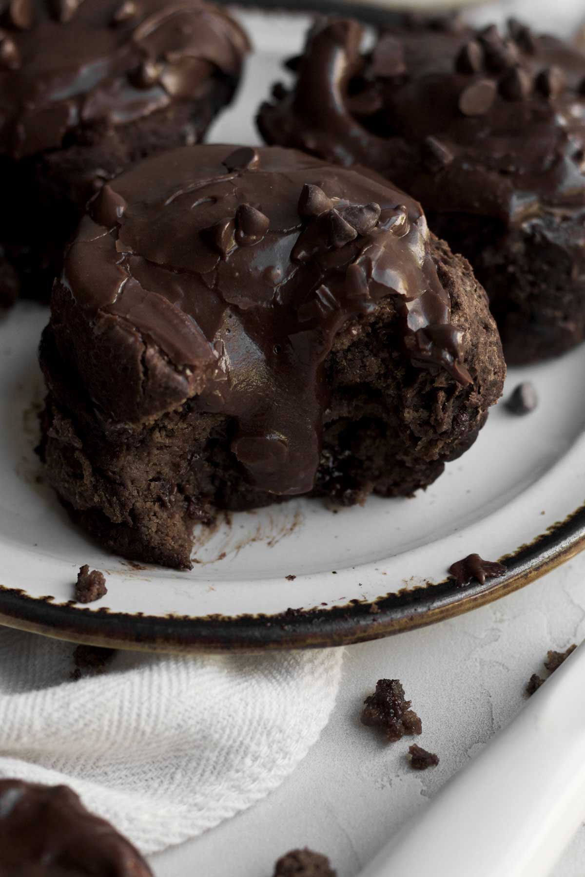 Warm chocolate cream cheese frosting descends down a bitten chocolate cinnamon roll.