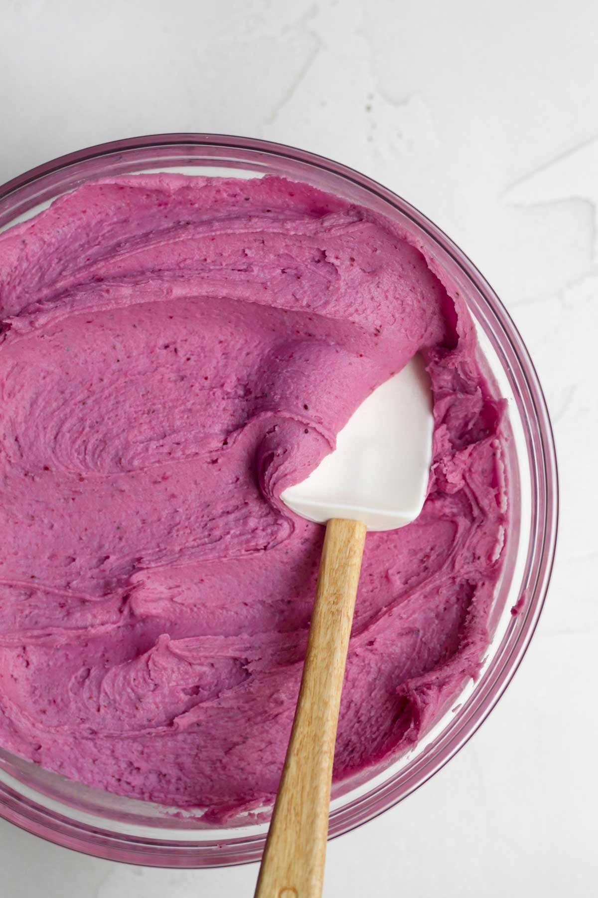 A spatula with creamy magenta blueberry frosting.