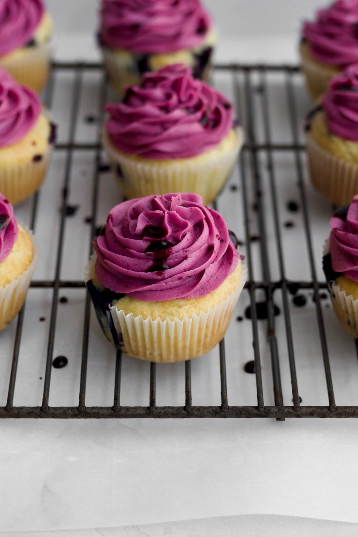 Drizzling on blueberry liquid to the top of the blueberry cuopcakes.