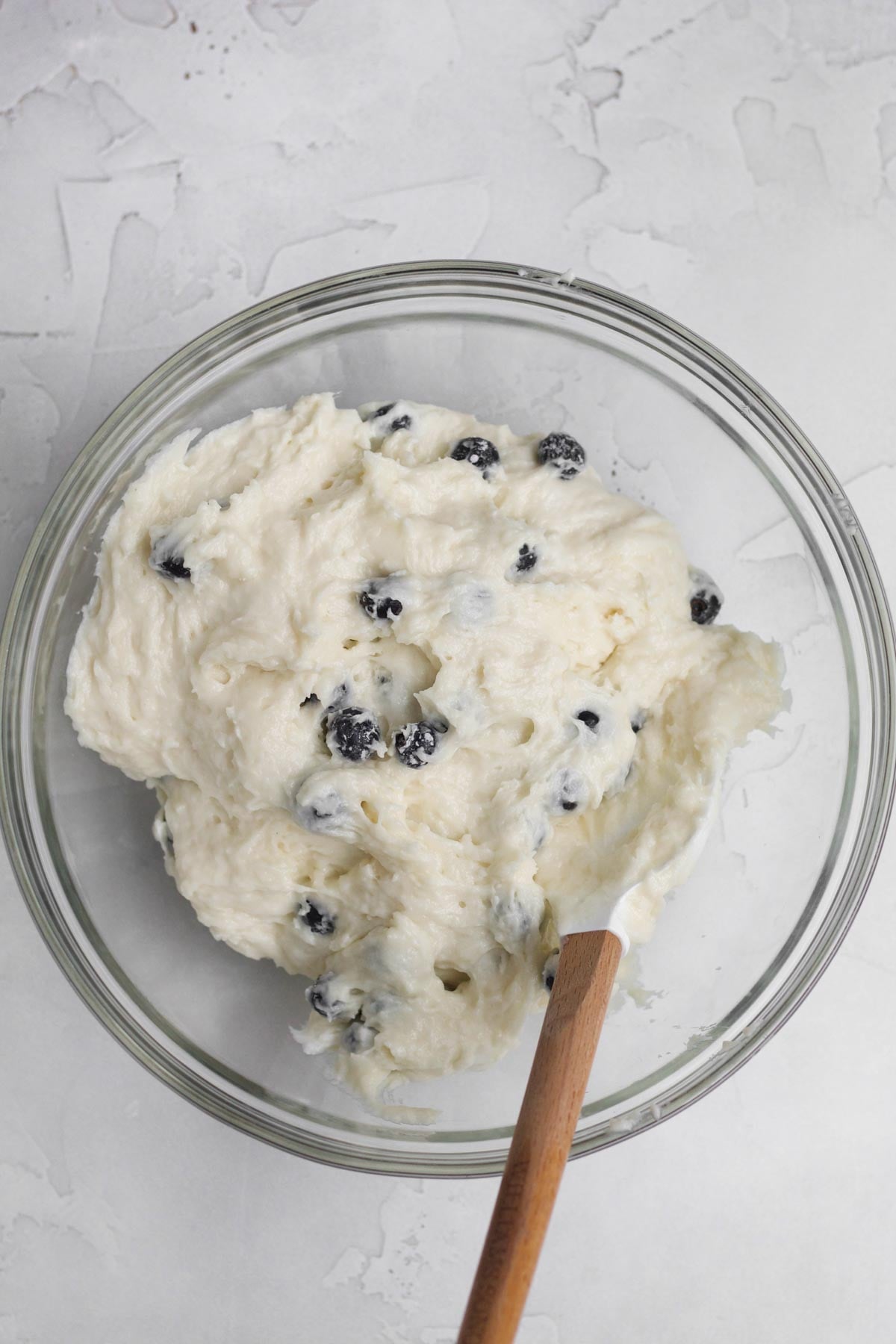 Folding in whole fresh blueberries into the batter.
