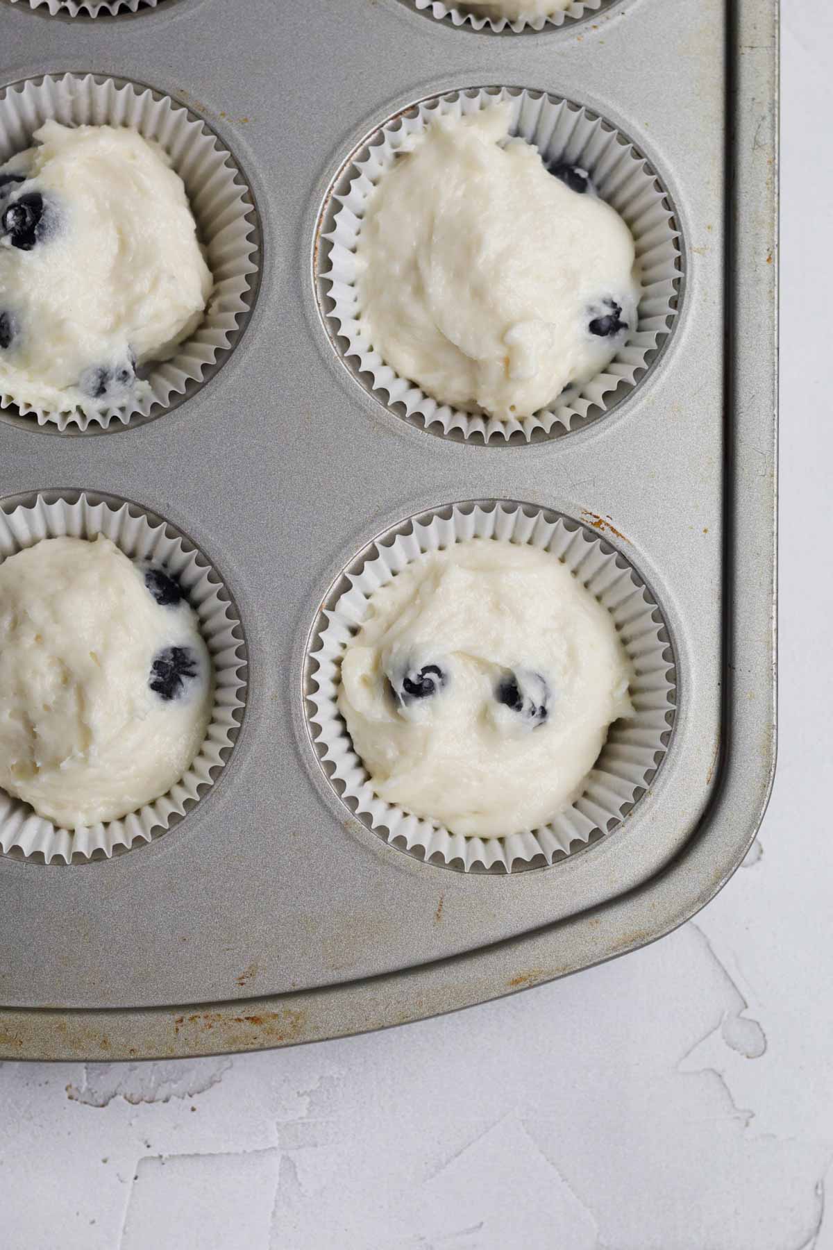 Filling a lined cupcake tin with the blueberry cupcake batter.