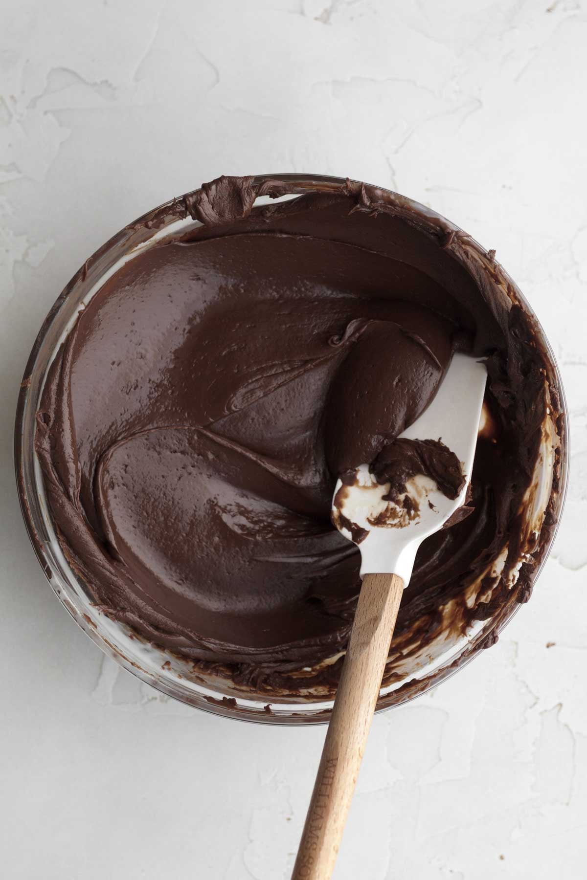 Rich chocolate fudge in a bowl with a spatula.