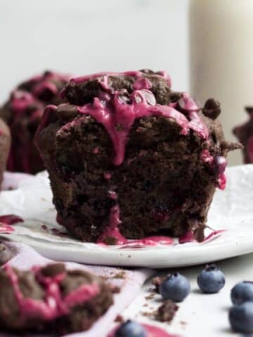 A halved chocolate blueberry muffin with its soft crumb interior with melted chocolate chips and bursted blueberries.