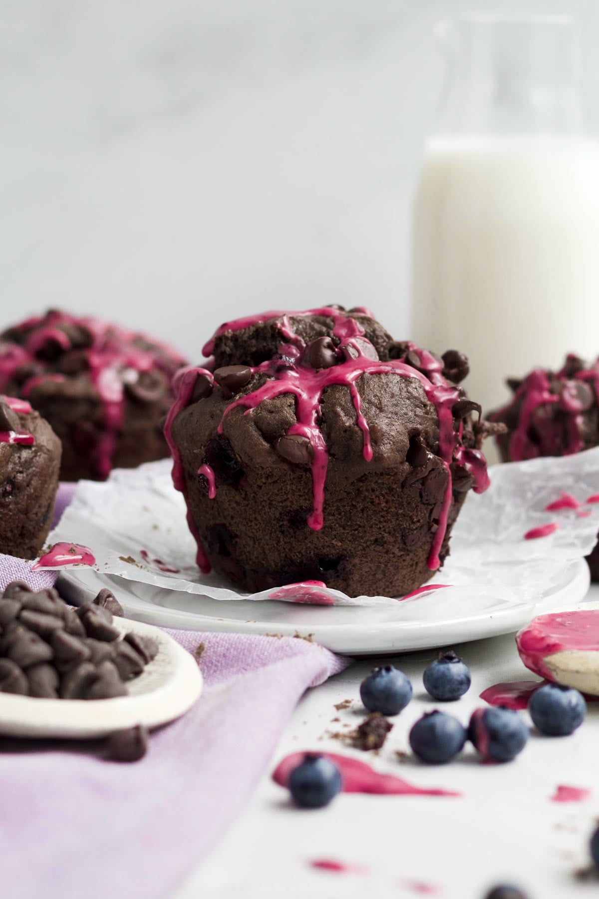 Giant gluten-free chocolate blueberry muffins with a bright pink blueberry icing drizzle.