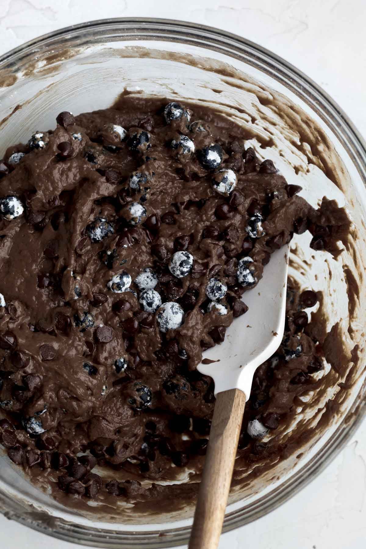 Mixing the wet and dry ingredients together and folding in blueberries and chocolate chips.