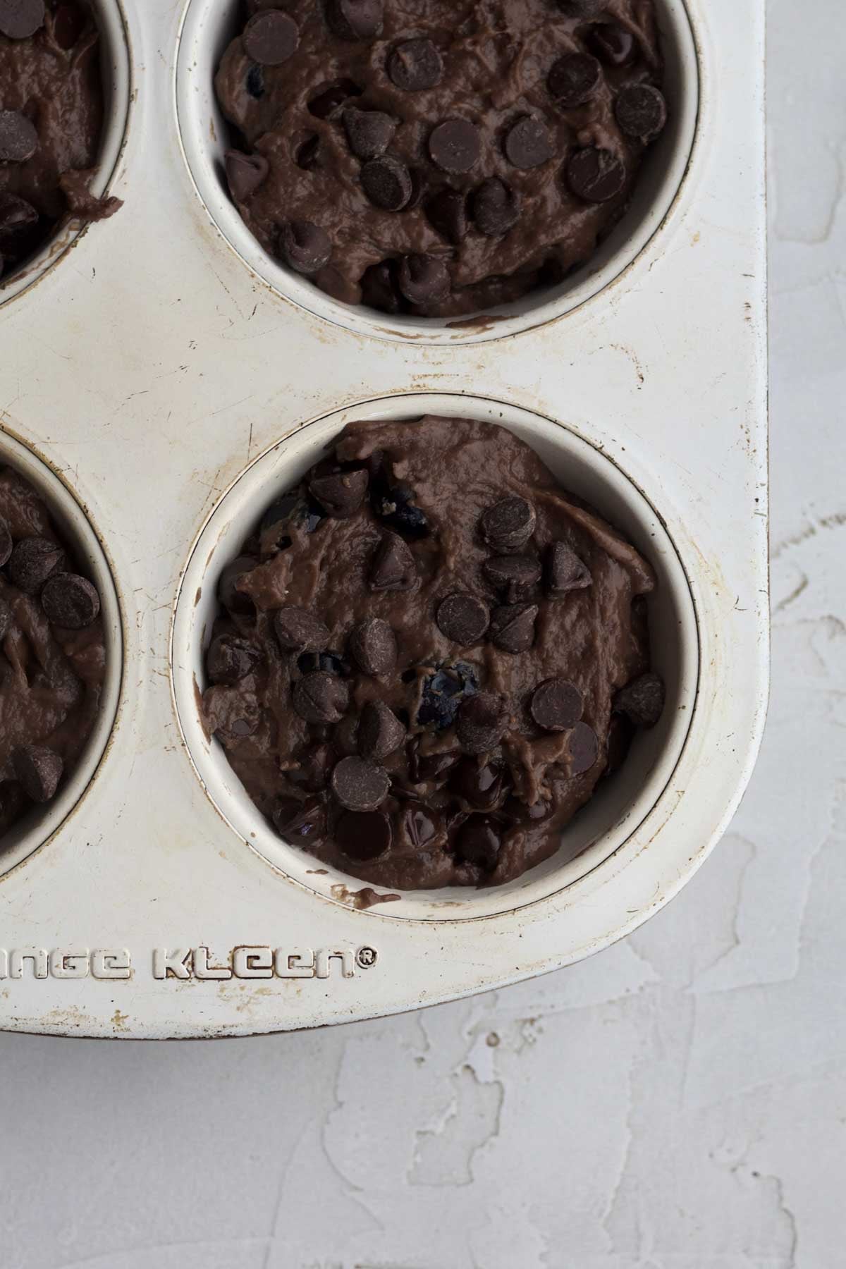 Filling a large muffin tin with the chocolate blueberry muffin batter.