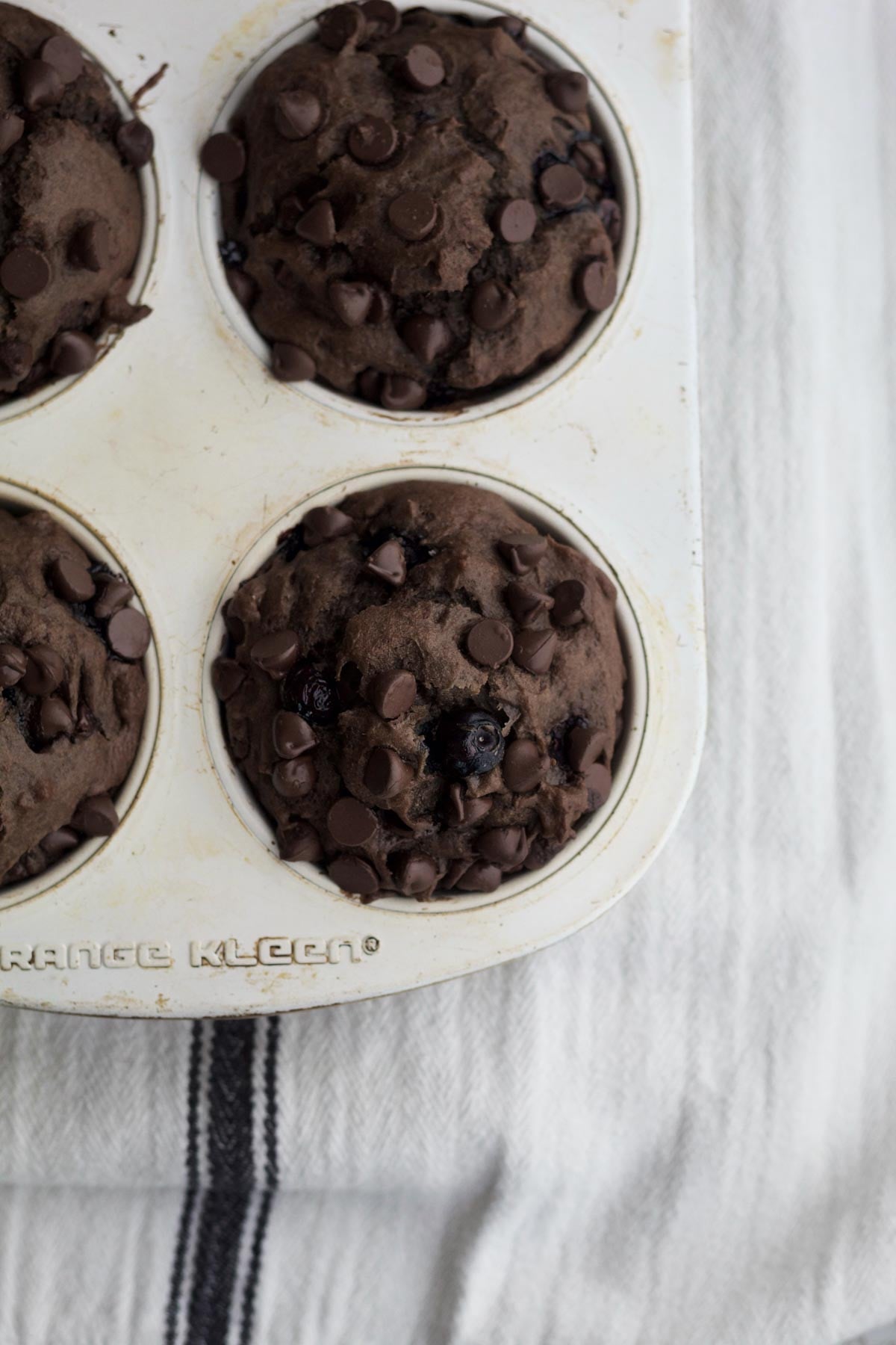 Fresh, dark and delicious chocolate blueberry muffins risen in the tin.