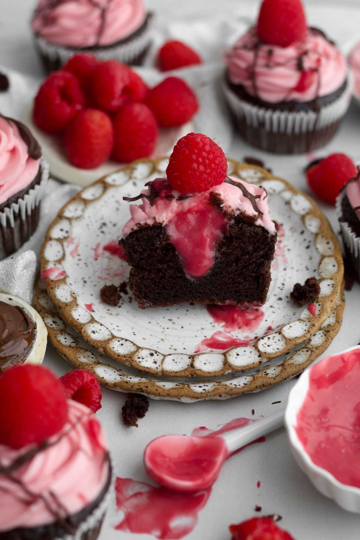 A chocolate raspberry cupcake halved exposing a thick drip of its raspberry curd filled center.