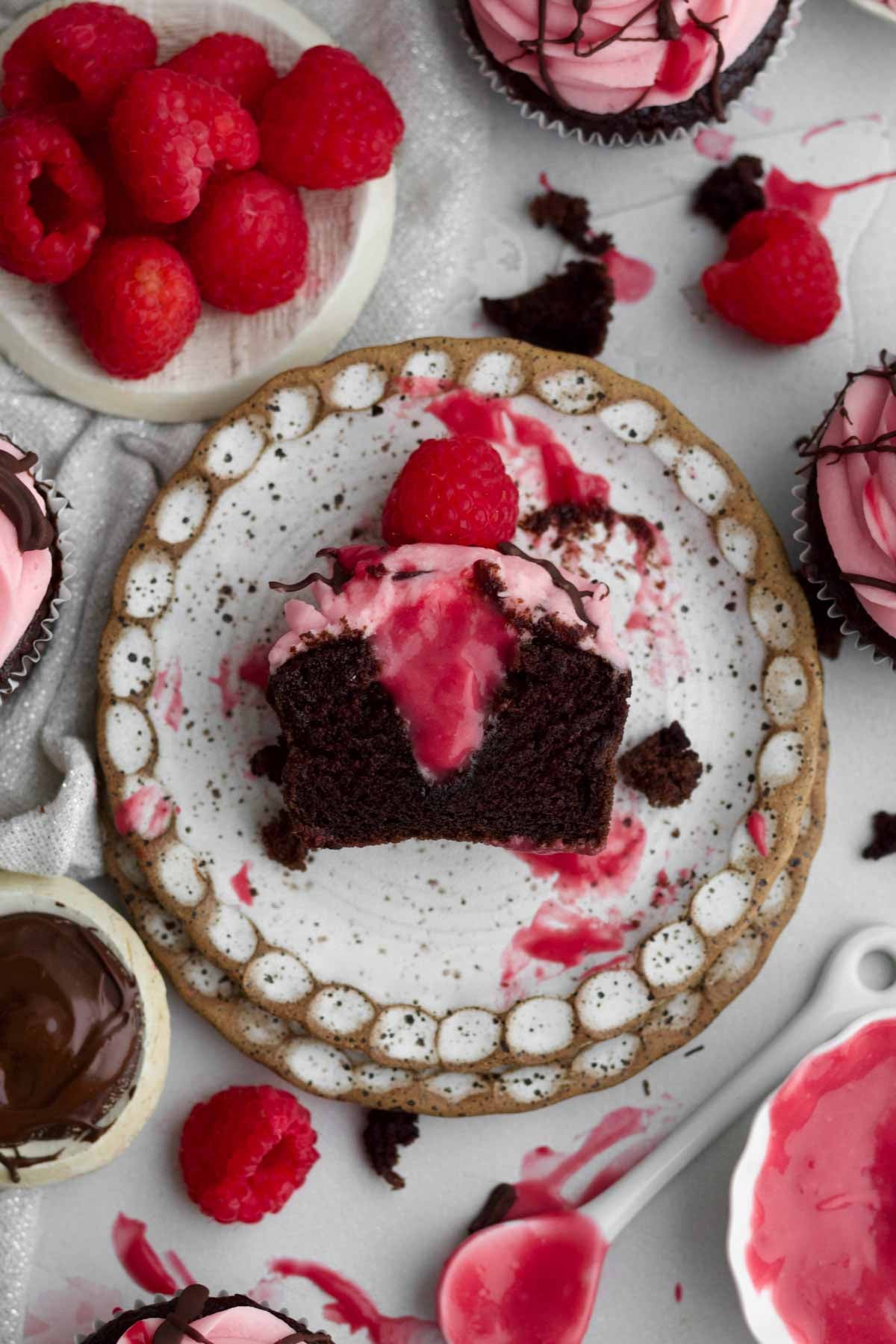 A halved chocolate raspberry cupcake with its' tender crumb and sweet curd and frosting.