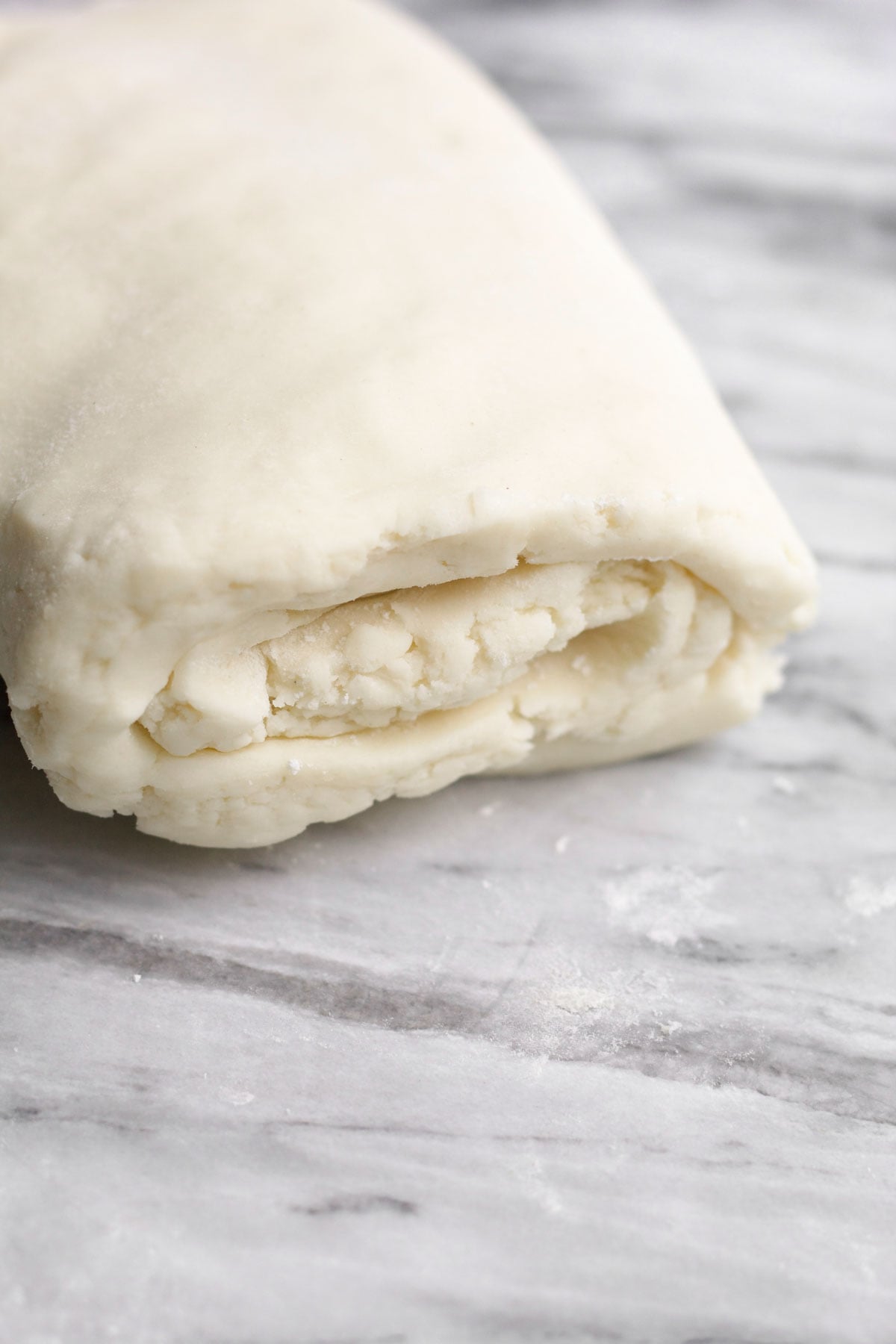 Easy puff pastry dough rolled and flattened on marble.