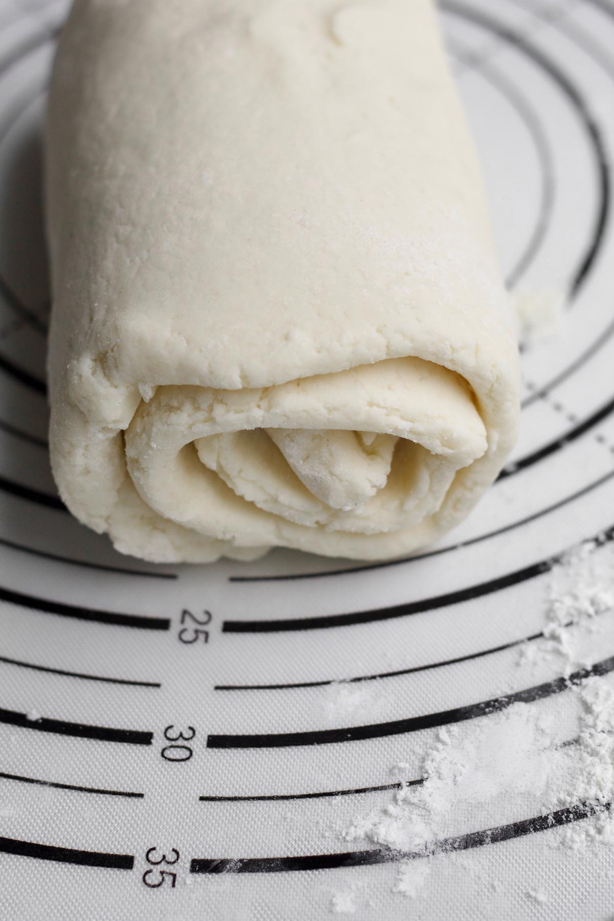 Rolled up puff pastry dough on a cutting board.