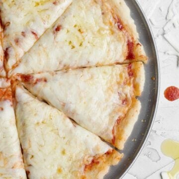 Slices of baked gluten free pizza dough topped with melted mozzarella cheese and red tomato sauce.