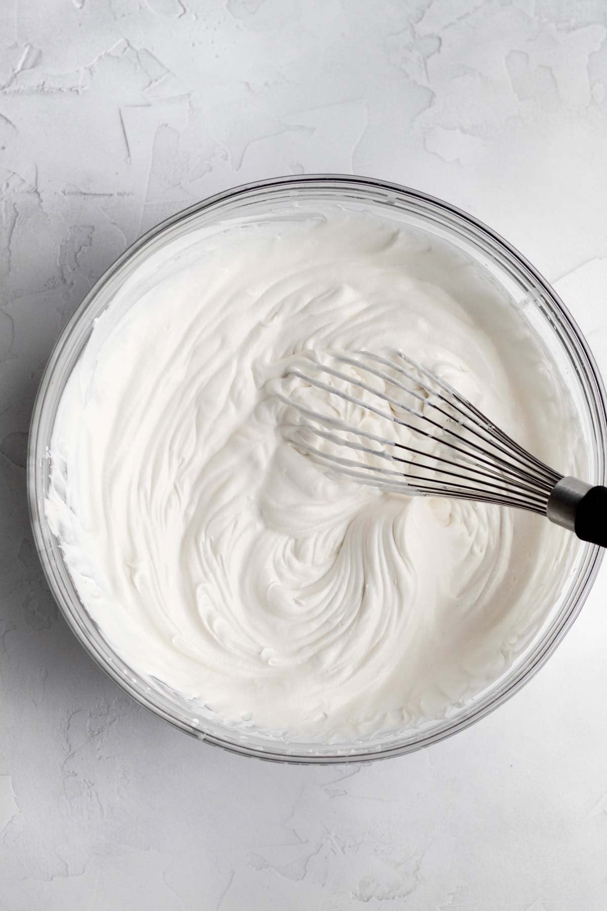 Heavy cream whipped up in a bowl with a whisk.