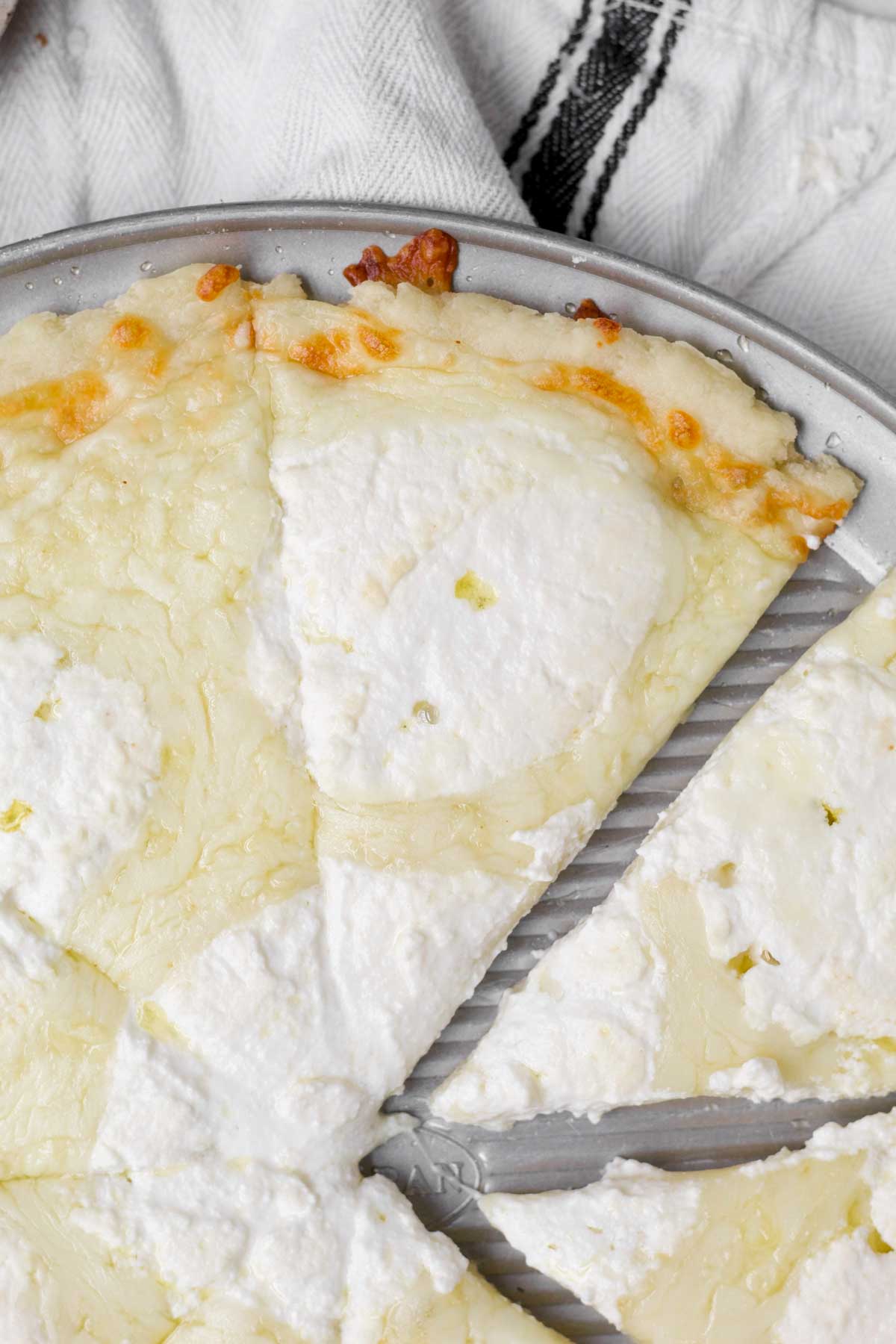 Slices of glutenfree pizza bianca (white pizza) with warm melted cheeses and golden crust.