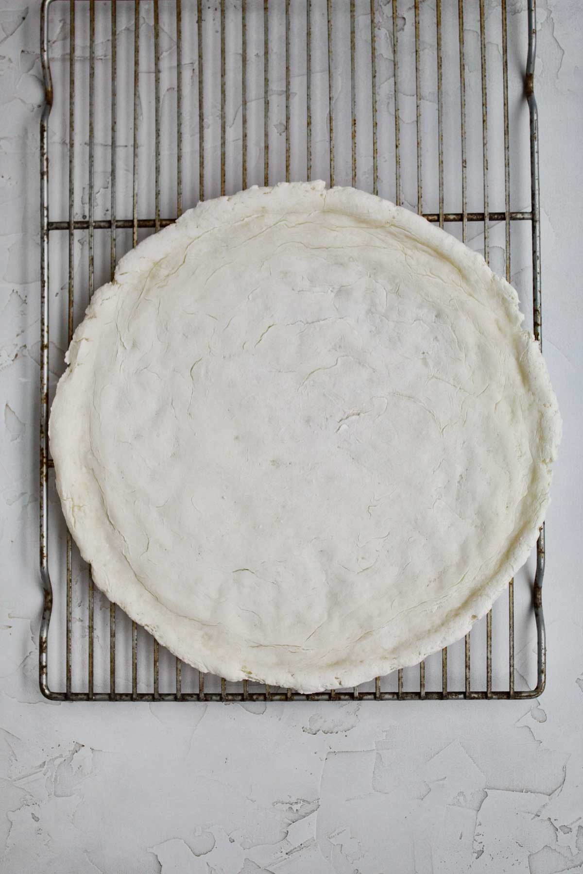 Baked gluten free pizza crust on a wire rack.