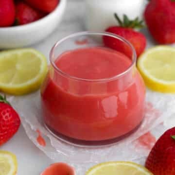 Bright red, creamy strawberry curd in a glass jar.