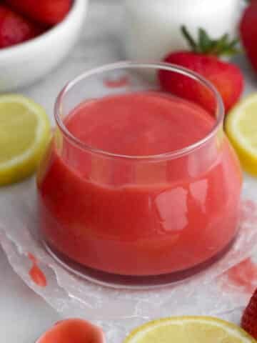 Bright red, creamy strawberry curd in a glass jar.