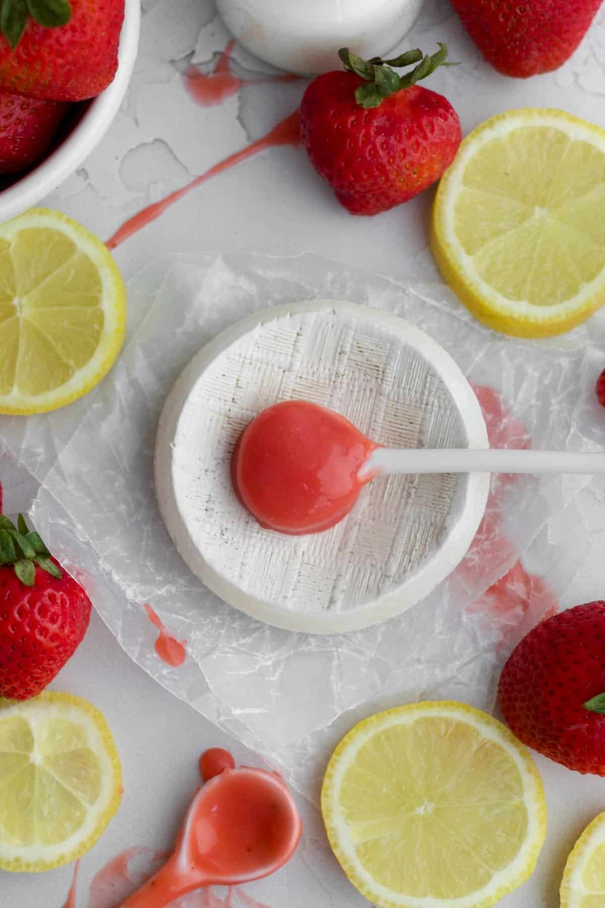 A dollop of sweet strawberry curd on a ceramic spoon on a plate.