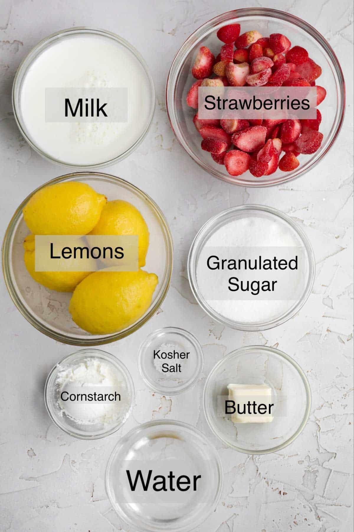 Strawberry curd ingredients in separate bowls: milk, strawberries, lemons, granulated sugar, cornstarch, kosher salt, butter and water.