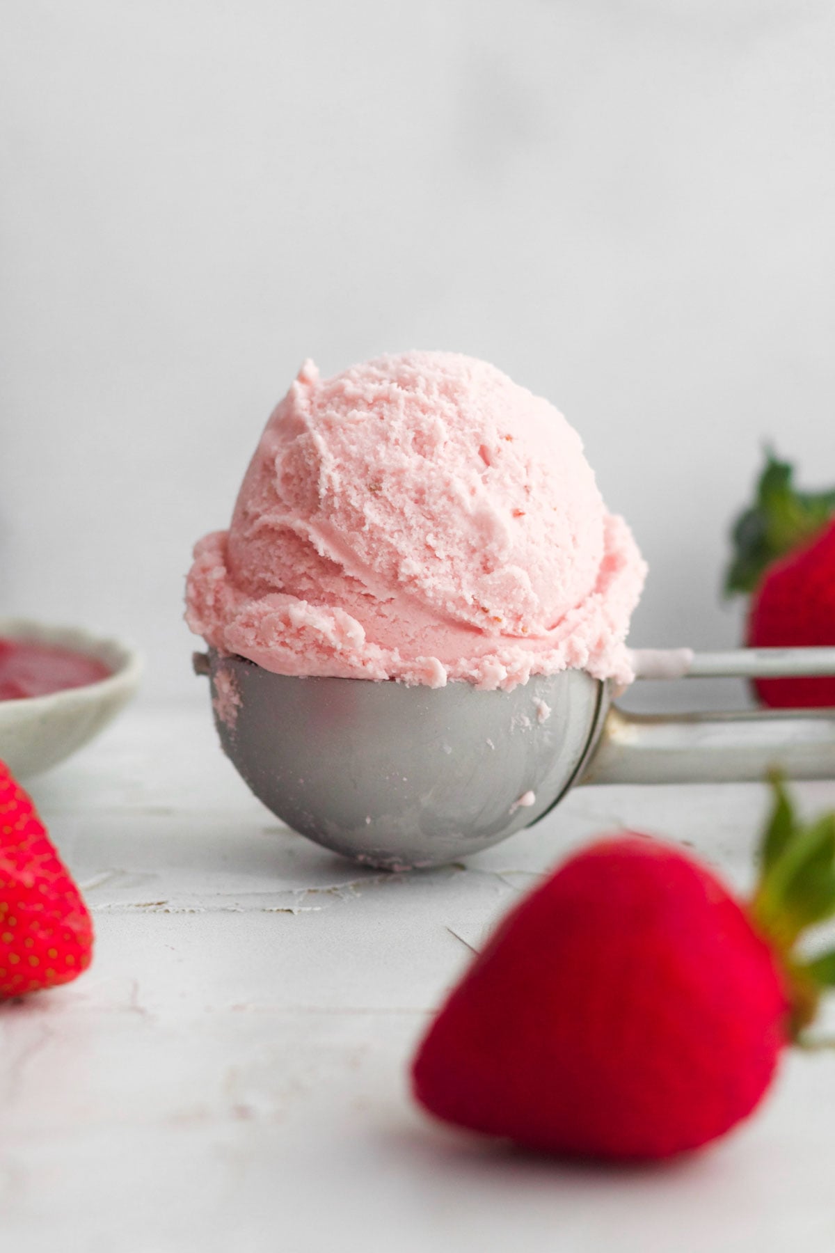 A creamy pink scoop of delicious strawberry ice cream in a silver scoop.