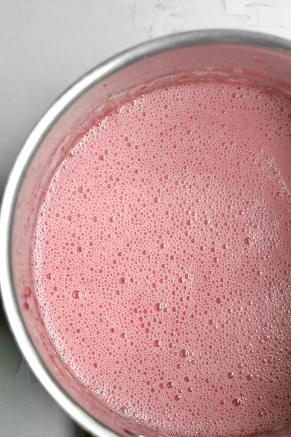 A saucepan of cooked strawberries, sugar and salt.