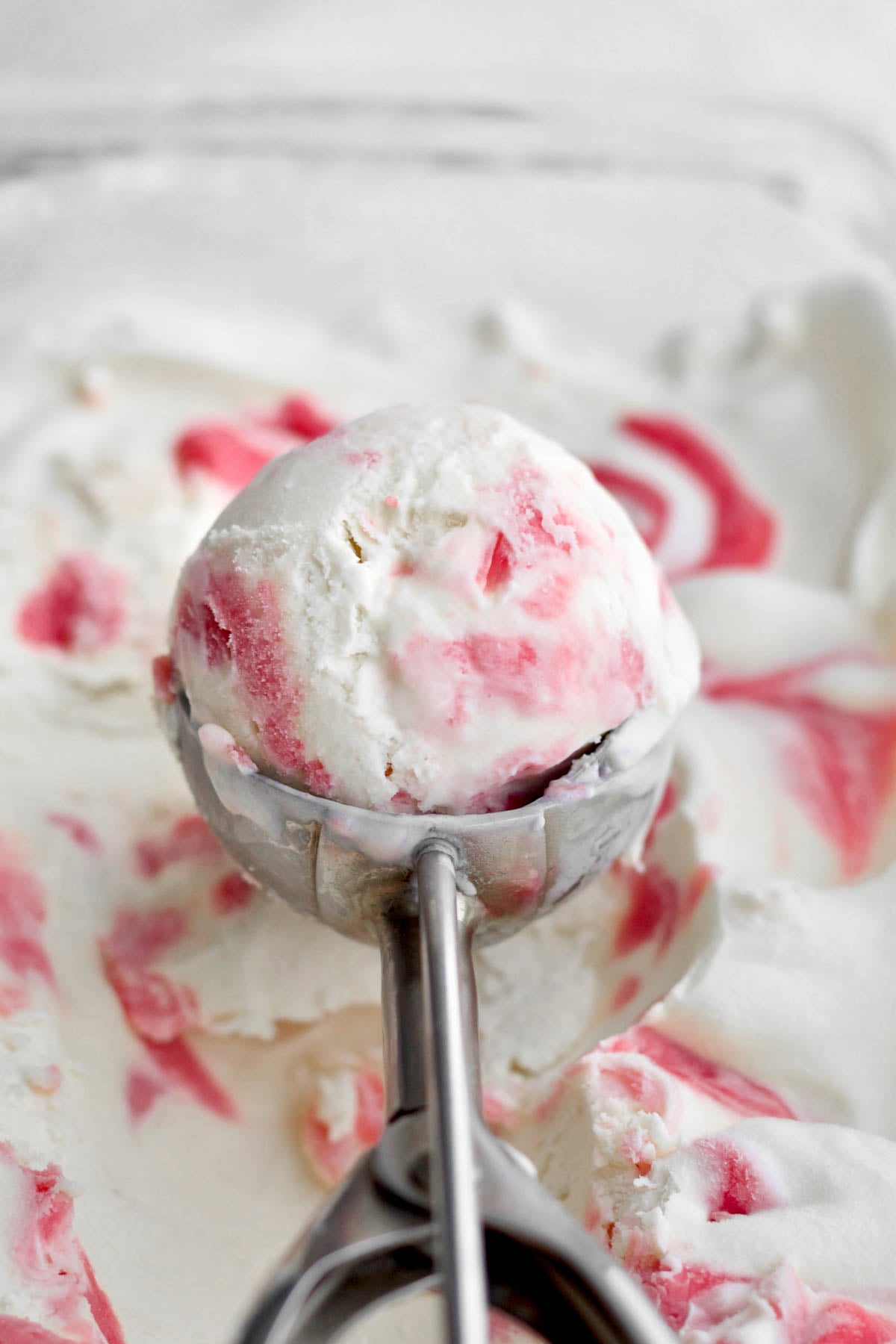 Delicious strawberry swirl ice cream in a scoop above the ice cream dish.