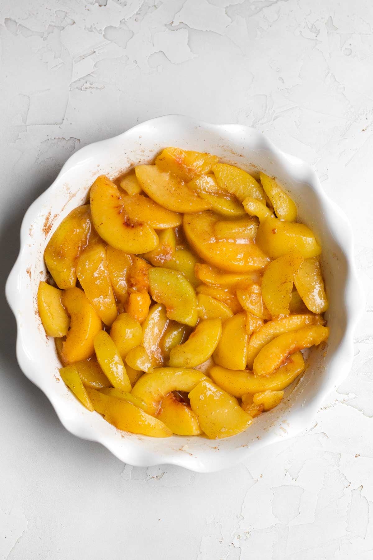 Bright orange peaches mixed with salt and sugar in a dish.