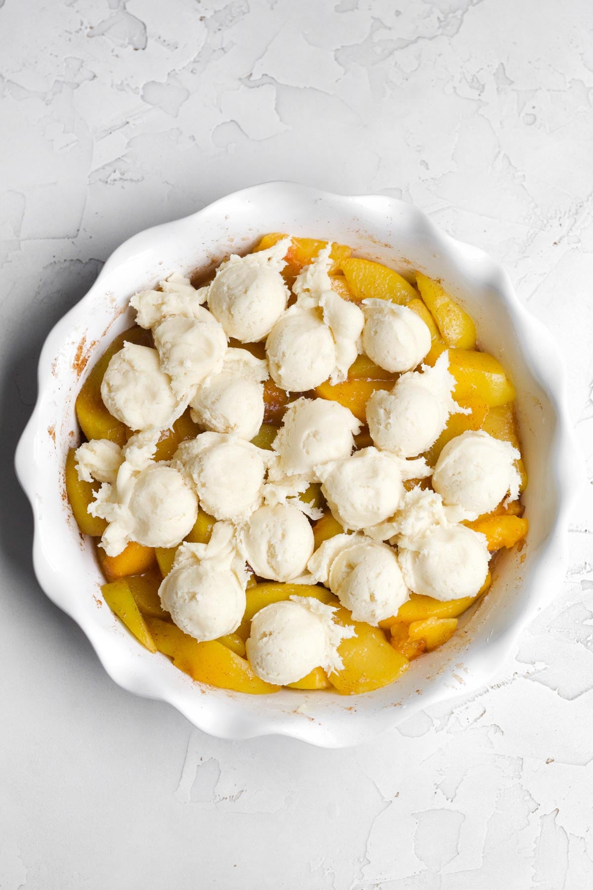 Scooping small batter balls onto the peaches.
