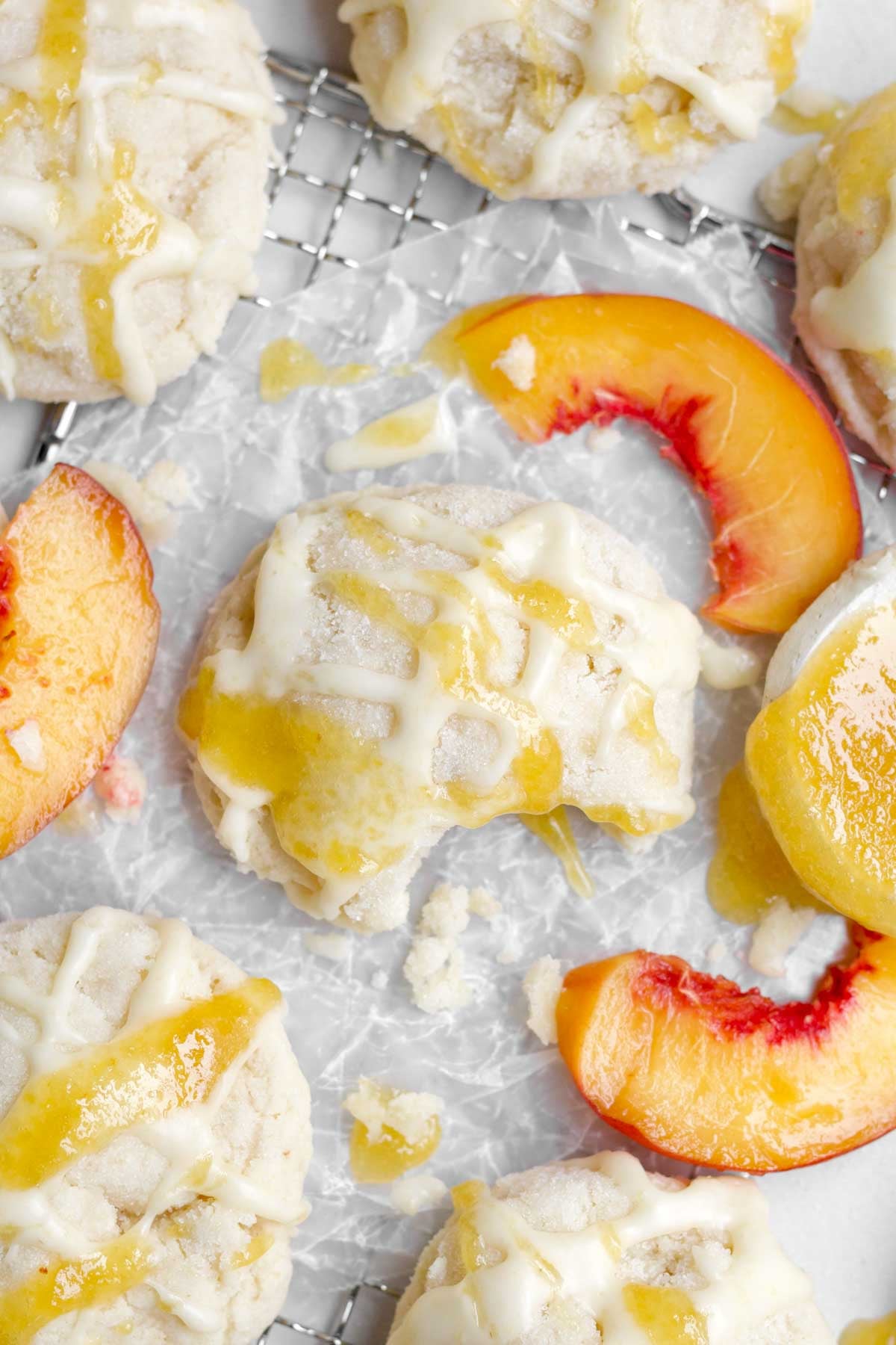 A bitten peach cookie amongst fresh peach slices.
