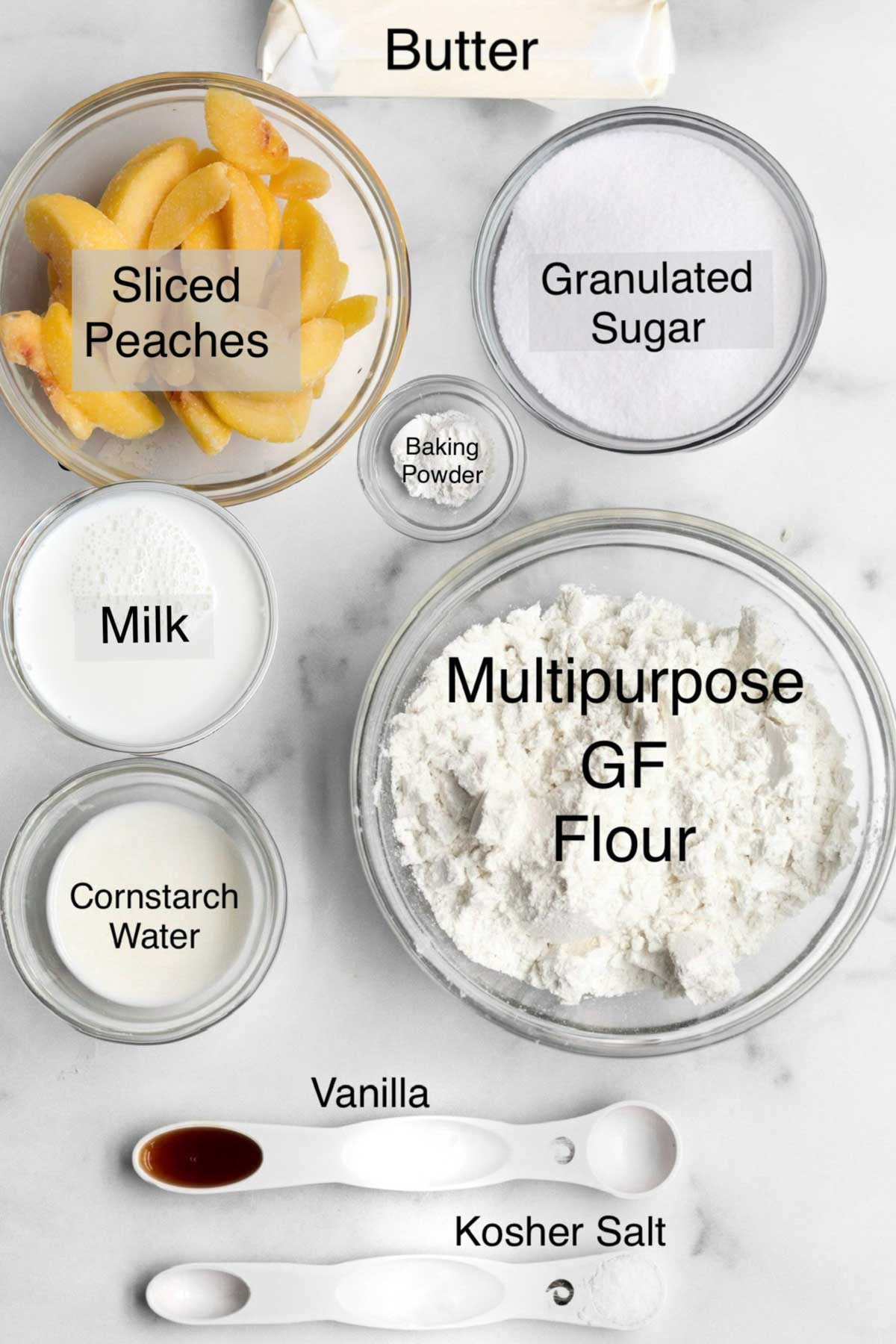 Peach cookies ingredients in separate bowls: butter, sliced peaches, granulated sugar, baking powder, milk, multipurpose gluten free flour, cornstarch water, vanilla, and kosher salt.