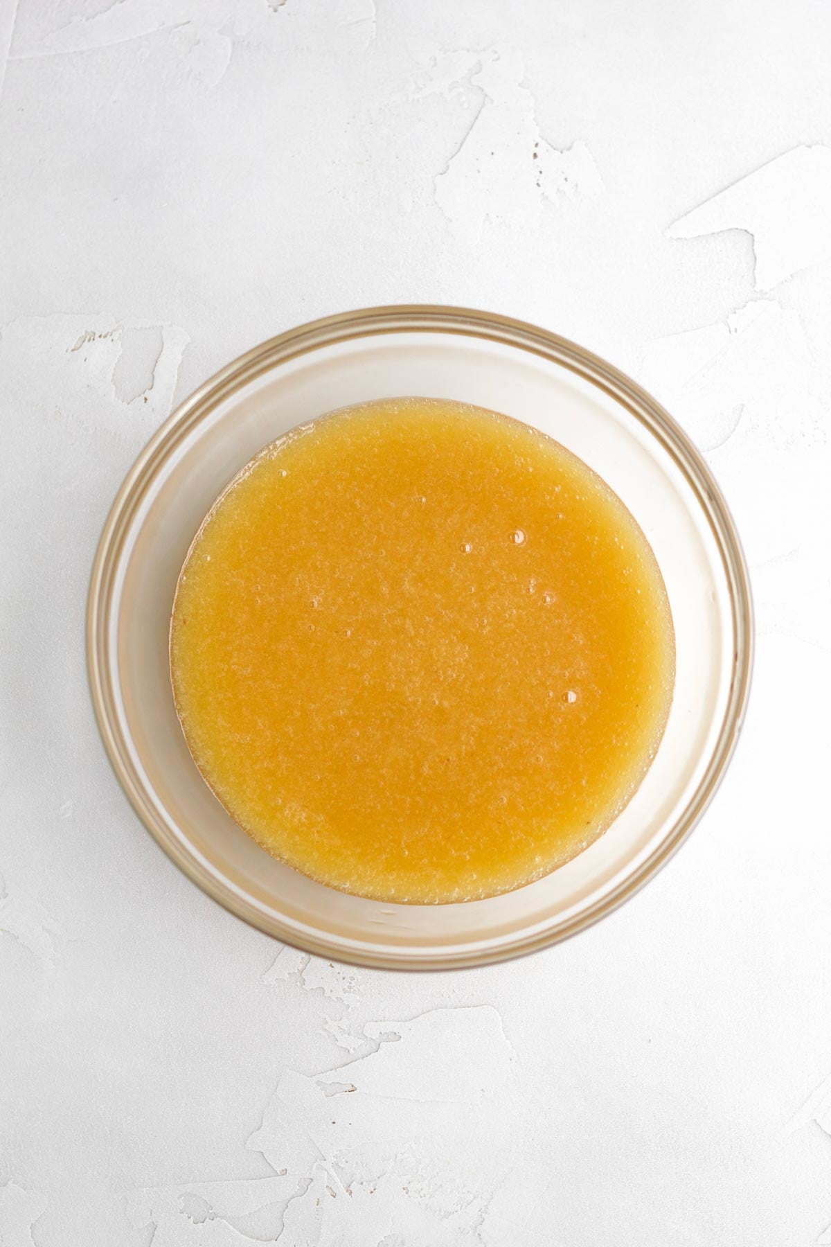 Strained orange peach liquid in a glass bowl.