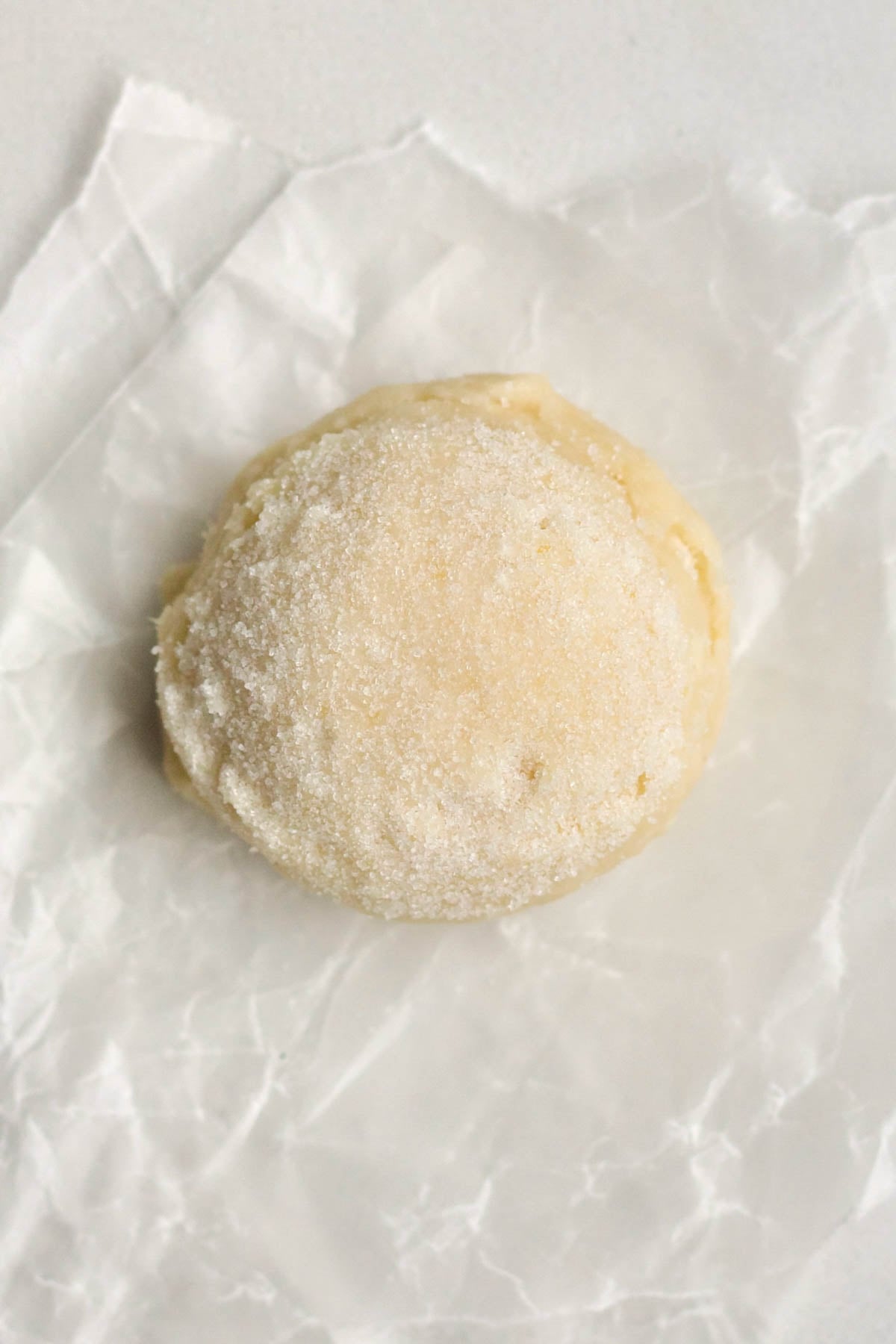 A scooped ball of peach cookie dough with a coat of granulated sugar.