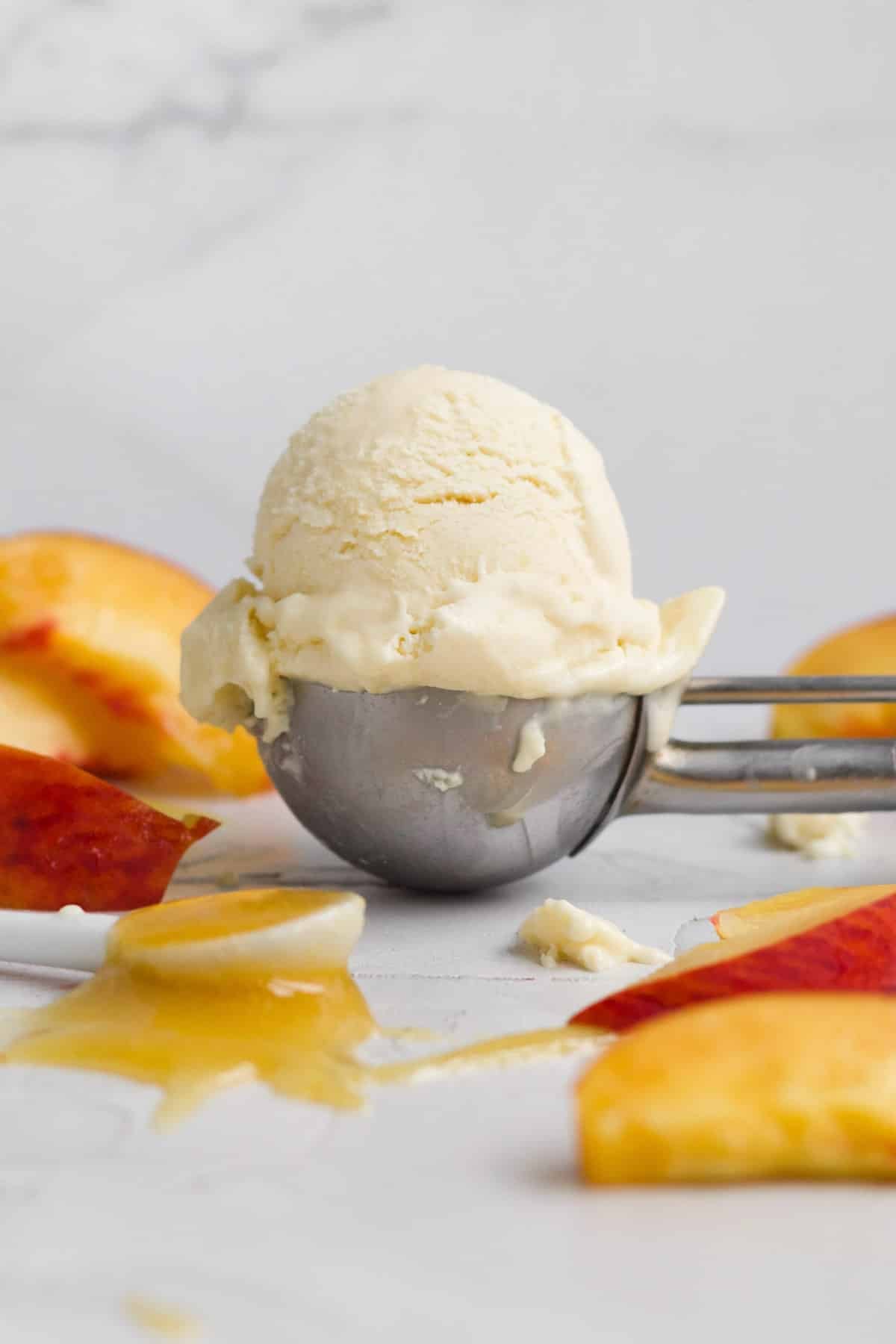 A delicious peach ice cream ball in a silver scoop.